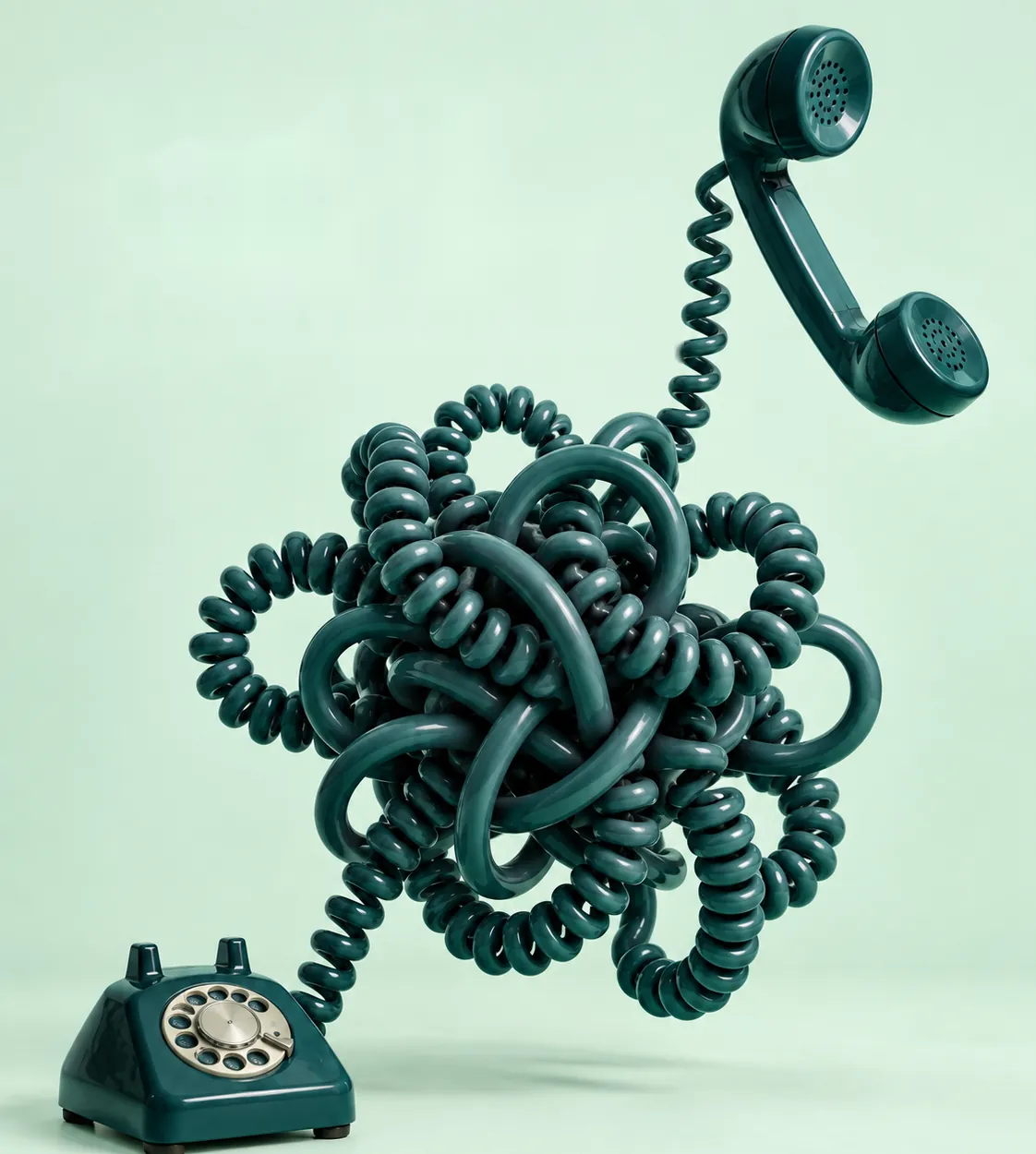 A vintage teal telephone whose coiled cord is tied in a huge tangle before reaching the handset