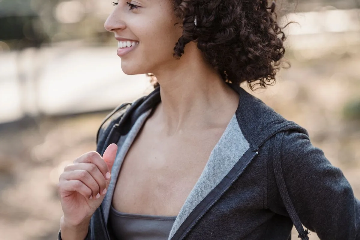 A woman smiling as she jogs outdoors